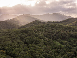 Sunlight breaks through clouds over serene green mountains