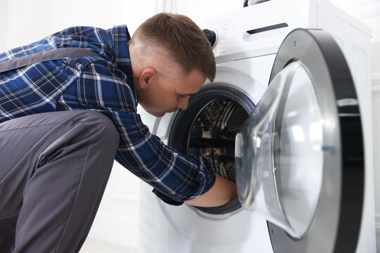 Repairman fixing broken washing machine at home