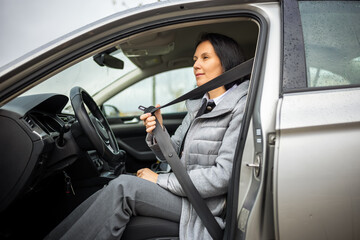 Middle-aged woman fastening seat belt in car