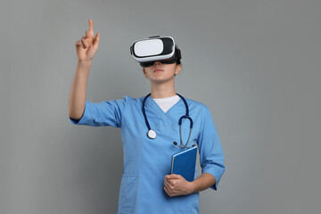 Modern technology. Doctor in headset using virtual screen on grey background