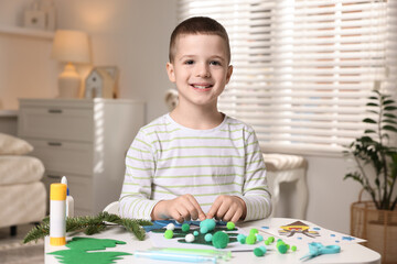 Little boy making Christmas postcard at table indoors. Child handmade craft