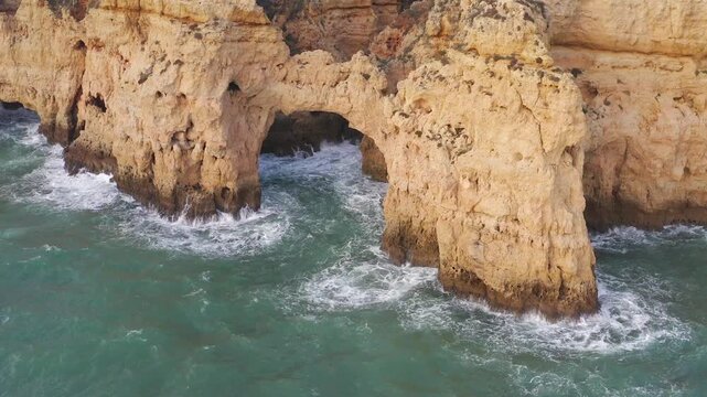 Natural Sea Cliff Formation With Arch Over Crystal Ocean Waves in Algarve, Portugal