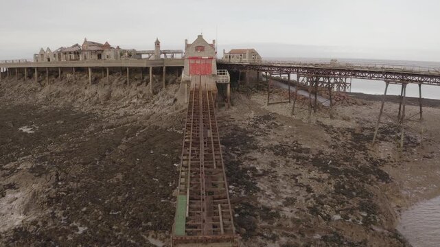 Close Aerial shot flying over Backlit Historical Coastal Ruins of Birnbeck Pier in Weston-Super-Mare United Kingdom