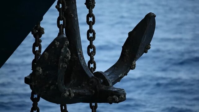 A weathered anchor suspended by chains, contrasting against the vast ocean.