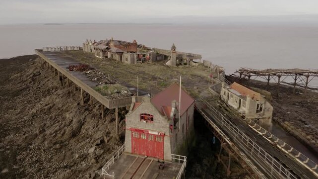 Low angle aerial retreating past the derelict iron pier of Birnbeck Pier in Weston Super Mare