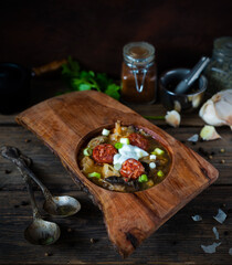 Christmas cabbage soup kapustnica with mushrooms in a wooden bowl on a natural background with spices and garlic in the background.