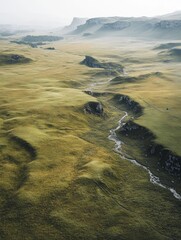A breathtaking view of a mountainous valley with a winding stream, captured from above. The landscape is rugged and untouched by civilization, creating a serene yet powerful scene.
