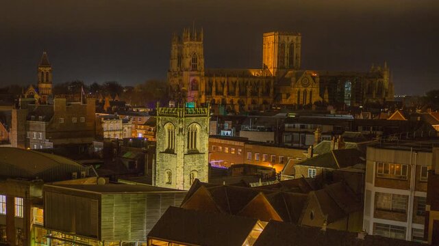 Night timelapse of historic illuminated York Minster Cathedral UK surrounded by cityscape buildings