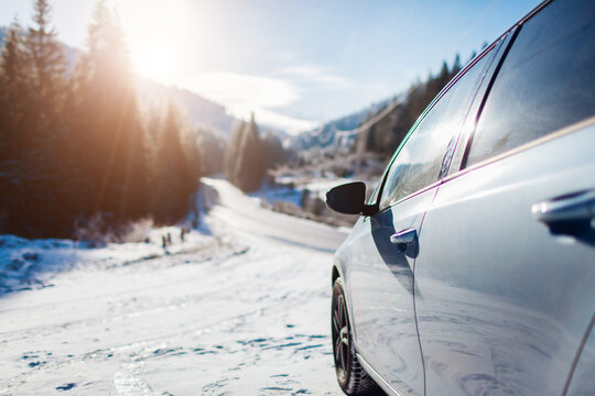 Traveling in winter by car. Holiday trip to snowy mountains. Blue auto stopped by frozen forest in Carpathians. Space