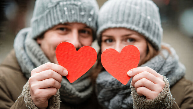 Couple heureux tenant chacun un coeur rouge