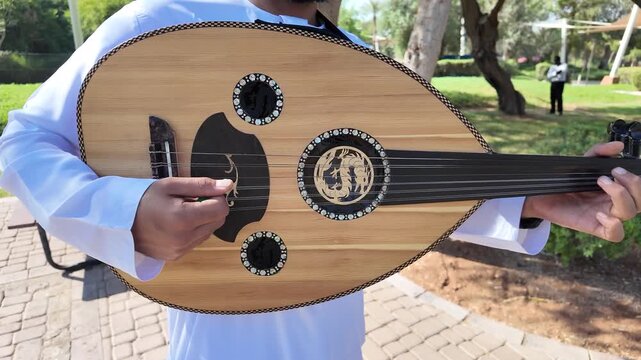 A person playing an oud, a prominent stringed instrument in Middle Eastern music at celebration of The United Arab Emirates Independence Day ( 54th uae national day ) in Al Ain Zoo 