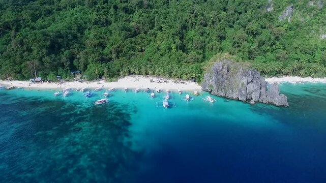 Seven Commandos and Papaya Beach in Palawan, Sightseeing Place. Tour A in El Nido, Philippines. Serene white sand beach with clear turquoise water, palm trees rock formations in Background. Drone
