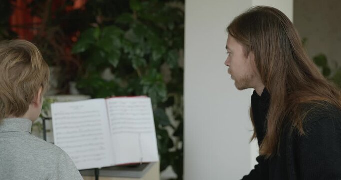 Male Teacher Gives Music Lesson for a Child. Man is Teaching Kid to Play Musical Instrument. 4K 10-bit