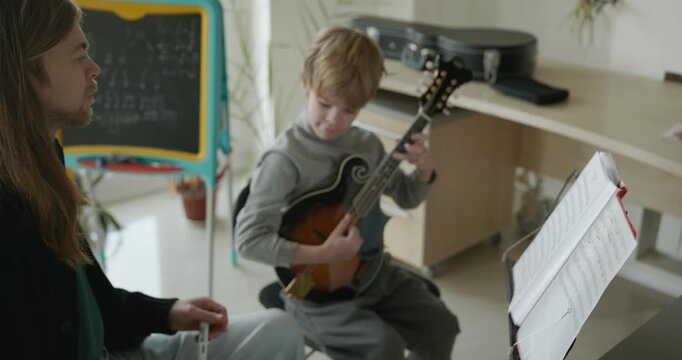 Male Teacher Gives Music Lesson for a Child. Man is Teaching Kid to Play Musical Instrument. 4K 10-bit