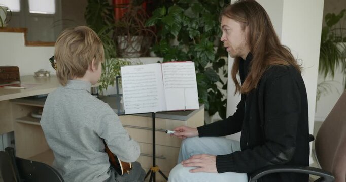 Male Teacher Gives Music Lesson for a Child. Man is Teaching Kid to Play Musical Instrument. 4K 10-bit