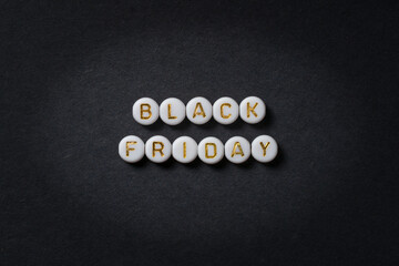 Black Friday text made of round beads in gold letters on black paper, advertising banner with space for text. High-resolution photo. Discount cards.