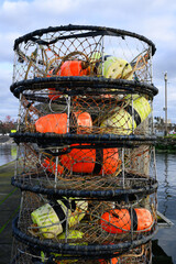 Fototapeta premium Pile of fishing crab pots with colored floats on pier stacked vertically