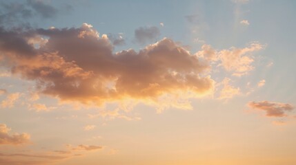 Fototapeta premium Orange sunlight gives the puffy clouds a warm glow as they float across the pale blue sky.