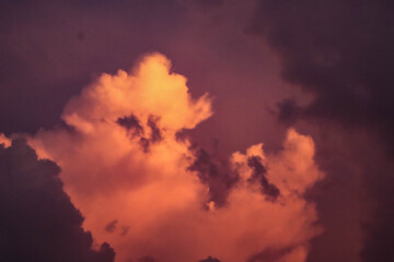 Fototapeta premium Intense orange and purple cumulus clouds vividly lit by the setting sun during twilight.