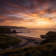 Obraz premium A stunning landscape photograph captures a coastal scene during a vibrant sunset. The composition is a wide shot, presenting a panoramic view of the beach, sea, and sky. 