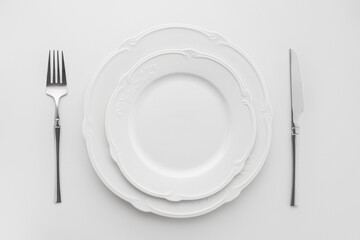 White plates with cutlery on a white background