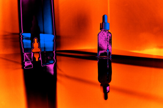 Vibrant neon abstract skincare serum bottle with dropper on reflective surface, colorful futuristic beauty product concept with glowing orange, blue and pink lights, modern cosmetic art composition