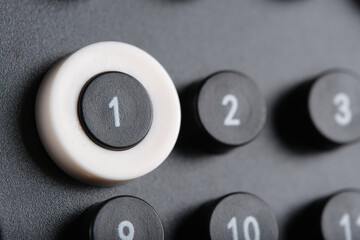 Macro shot calendar button marked 1 framed in white ring, surrounded by numbered buttons on dark minimalist background.