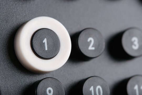 Macro shot calendar button marked 1 framed in white ring, surrounded by numbered buttons on dark minimalist background.