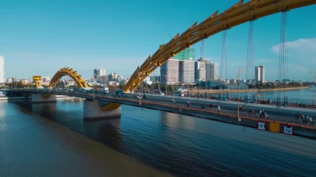 Golden Dragon Bridge over Han River in Da Nang at sunset, Iconic Vietnamese landmark over urban waterway with city skyline, aerial drone view 4k