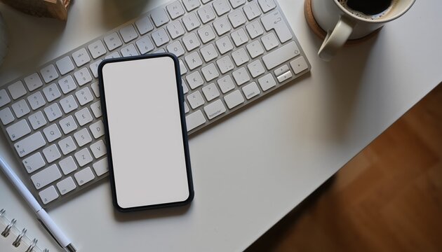 Workplace digital: A contemporary workspace setup, complete with a smartphone featuring a blank display, is presented alongside a keyboard and coffee cup - Powered by Adobe