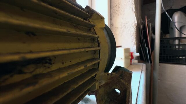 Home workshop. Electric motor for a sharpening machine. Close-up. Rusted metal