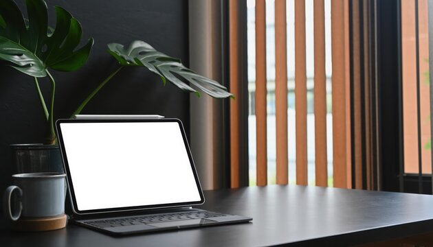 Workspace Serenity: A modern workspace comes alive with a digital tablet showcasing a blank display, a charming mug, and a vibrant plant, illuminated by natural light through a wooden-slatted blind. 