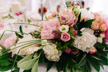 A delicate floral arrangement of pink and white peonies with small flowers decorates a festive table. Soft colors and greenery create a romantic, warm, and elegant atmosphere.  © Anhelina 