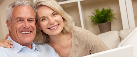 Happy Senior Man and Woman Couple Smiling at Home Using a Computer