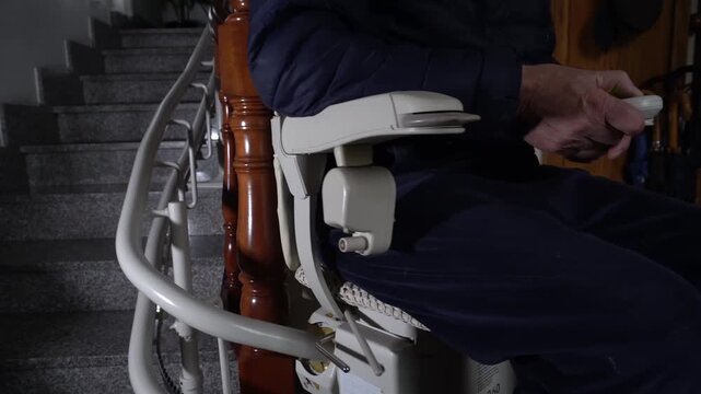 Electric lift chair installed on the interior stairs of a house. The white device contrasts with the dark wooden railing. Concept of accessibility, old age, care, security, home, mobility 