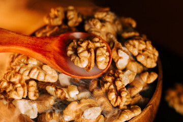 Peeled walnuts in a wooden bowl with a spoon resting on top