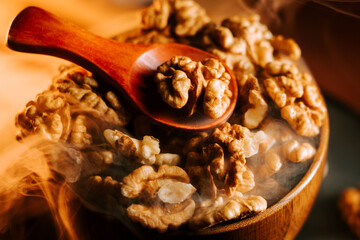 Peeled walnuts in a wooden bowl with a spoon on a table