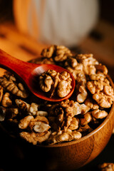 Peeled walnuts in a wooden bowl with a spoon on a rustic table