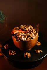 Peeled walnuts arranged in a wooden bowl with a natural wooden spoon on a dark background
