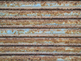 Frame texture of old rusted and peeling metal roller garage shutter door. Rust, oxidation, paint patches, distressed, textured industrial surface, decay, urban grit, deterioration, corrosion.