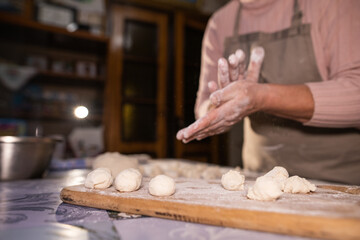 Grandma is making balls of dough for dumplings