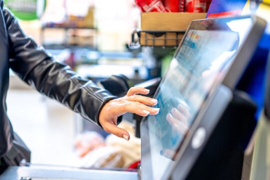 Woman Pressing Monitor At Self-Service Checkout