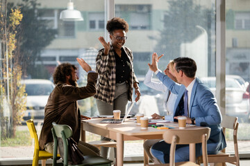 Diverse business team celebrating success with high fives