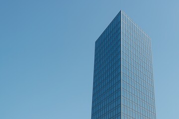 Highrise office tower with reflective glass windows against blue sky Space for text