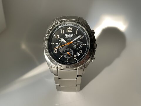 A sleek Casio Edifice chronometer watch is displayed prominently, featuring a black face and a silver metal strap casting subtle shadows.