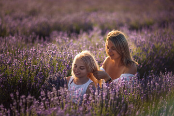 Mother daughter lavender field bonding adjusting hair at sunset, happy family memories