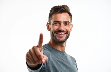 Young man points finger to side, smiling confidently. He presents product or idea. Represents choice, direction, or selection. White background for copy space.