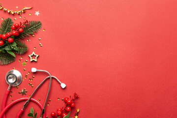 Christmas medical banner with festive sparkling decorations, fir tree branches and medical stethoscope on bright red background with copy space for your design.