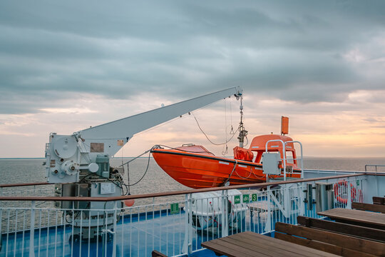 Orange rescue boat on a ferry deck during sunset sailing