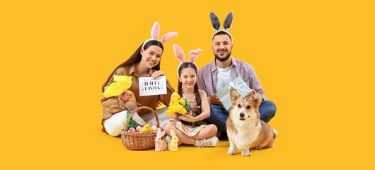 Happy family in bunny ears, with Easter gifts and funny dog on yellow background